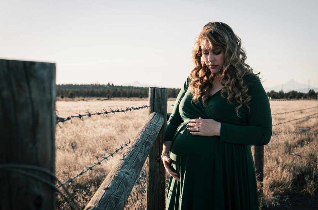 Femme enceinte en plein air, entourée de nature.